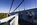 An on the bridge scene from Menai Bridge featuring the suspended steel, cables, safety barriers and tower of the World Heritage Site, Isle of Anglesey, Gwynedd